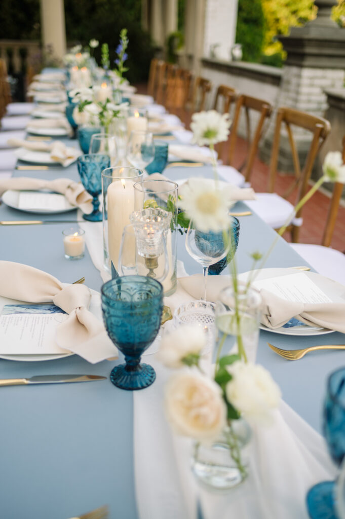 close up photo of long organic wedding centerpieces with floral bud vases and candles at villa terrace